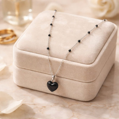 Collar de acero inoxidable con dije de corazón convexo esmaltado en negro.